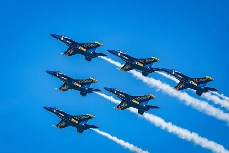 Six U.S. Navy Blue Angels jets fly in formation against a clear blue sky.