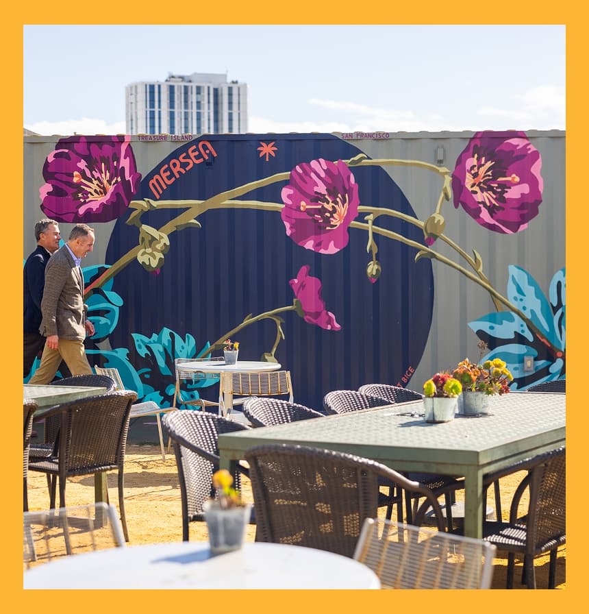 Outdoor dining patio on Treasure Island featuring colorful floral mural art and casual waterfront seating.